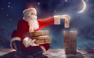 Дед Мороз на крыше дома бросает подарки в дымоход