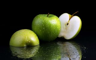 зеленые яблоки в капельках воды на черном фоне