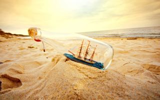 корабль в бутылке на песке пляжа возле моря
