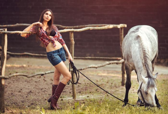 Картинка девушка в сапогах, шортах, рубашке возле заграждения с лошадью