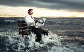 мужчина читает газету на лавочке посреди океана