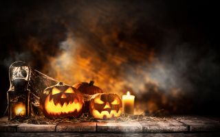 тыквы возле свечек в паутине, праздник Хэллоуин